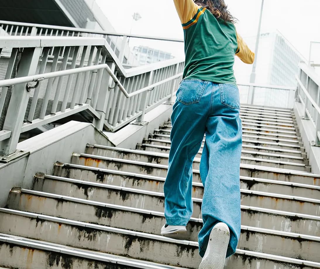 Person walking up wooden stairs in blue pants