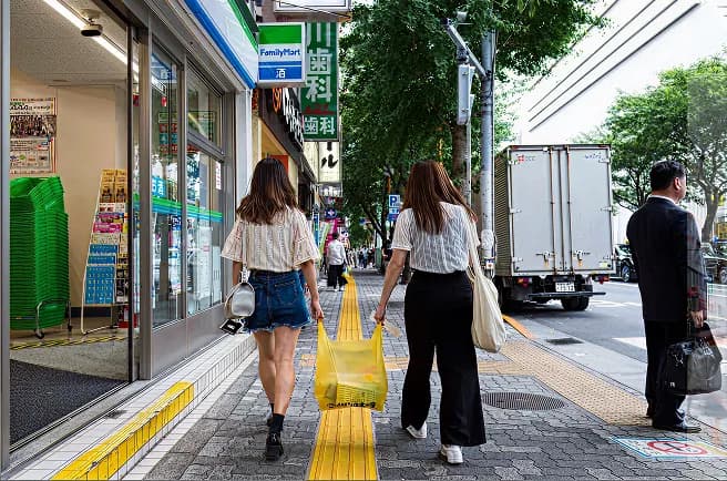 Two people walking past a convenience store on a city sidewalk