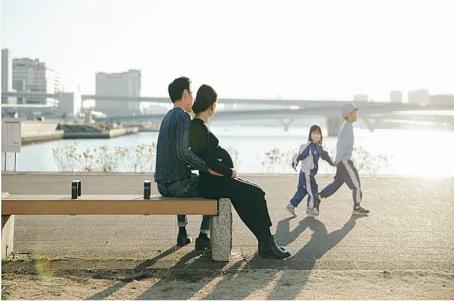 Couple sitting on a bench by the waterfront at sunset